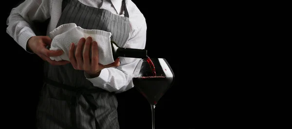 Bartender derrama vinho em banner de vidro no fundo escuro — Fotografia de Stock