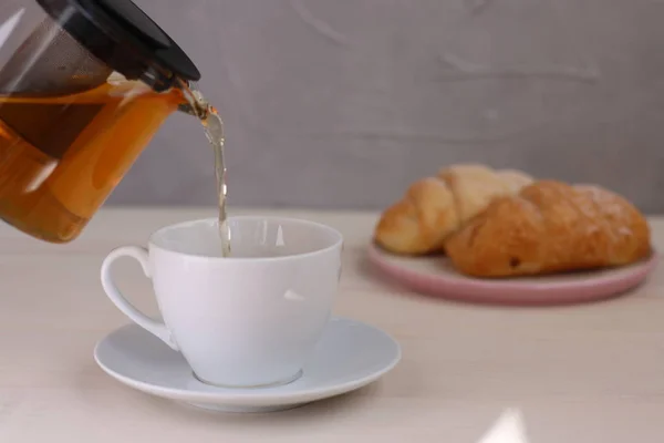 Τσάι που χύνεται σε Κύπελλο σε ελαφρύ φόντο. ιδέα για τσαγιέρα και πρωινό — Φωτογραφία Αρχείου