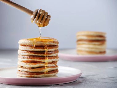 Bal kaşığı ile pancake yığını ve ışık arka planda bal dökme