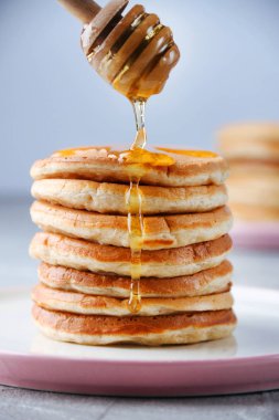 Bal kaşığı ile pancake yığını ve ışık arka planda bal dökme
