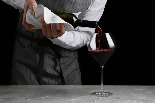 Червоне вино наливається в склянку. бармен на концепції офіціанта на чорному фоні — стокове фото