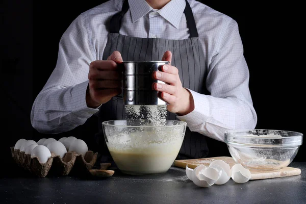 sifting flour in bowl. man cooking pie concept of dessert