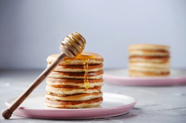 Bal kaşığı ile pancake yığını ve ışık arka planda bal dökme