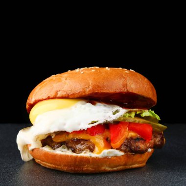 Esmer arka planda yumurtalı leziz taze hamburger. Taze sebze ve peynirli ev yapımı hamburger veya hamburger.