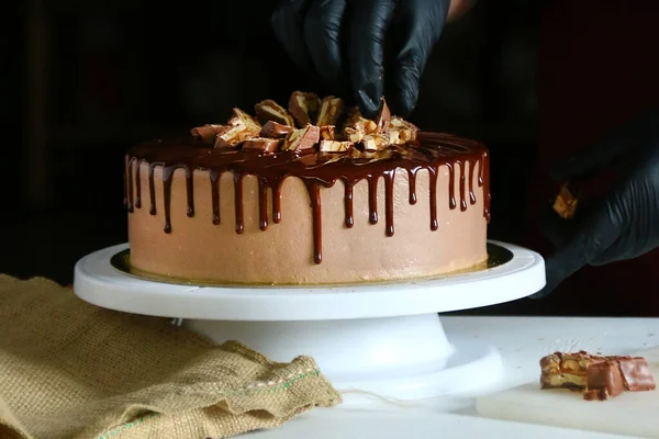 Cukrászati folyamat csokoládé torta az asztalon. A folyamat díszítő a torta folyékony csokoládéval. A folyamat, hogy a csokoládé torta sötét alapon — Stock Fotó