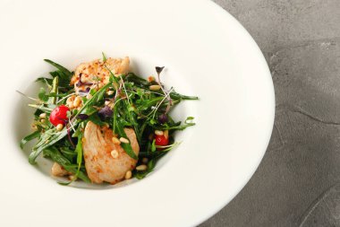 Tavuk roka ve çam fıstıklı salata. Beyaz tabakta yakın plan.