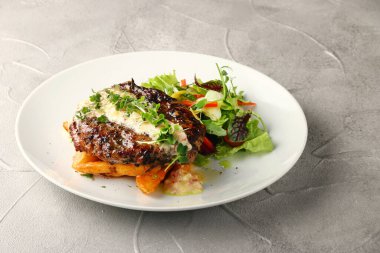 Patatesli ızgara biftek ve salata. Beyaz tabakta yakın plan ve beton sırt.