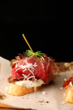 Biftek parmesanlı bruschetta ve ahşap kaplamalı mikroyeşil. Geleneksel İspanyol mezeleri. Üç tapas seti.