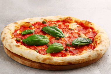 Kapari ve fesleğenli biberli pizza. Hafif beton, taş masa ya da sırta yakın plan.