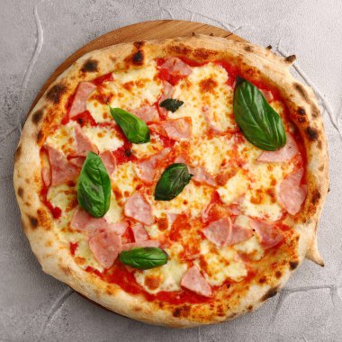 Jambonlu ve peynirli pizza. Hafif beton ya da taş masa.