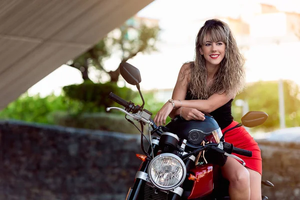 Szczęśliwa młoda kobieta siedzi na czerwonym motocyklu — Zdjęcie stockowe