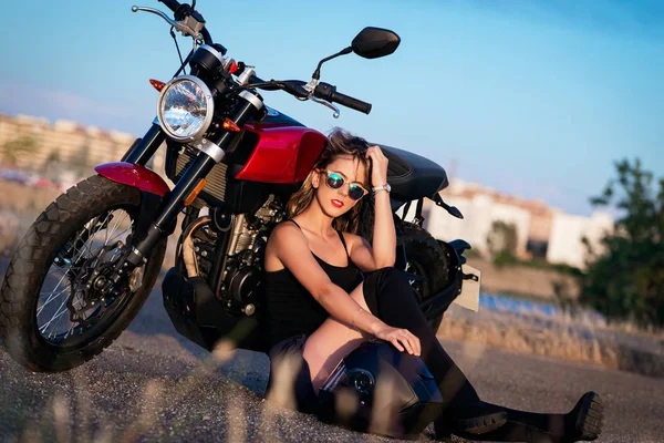 Young pretty  woman sitting on ground next to nake racer motorbi — Stock Photo, Image