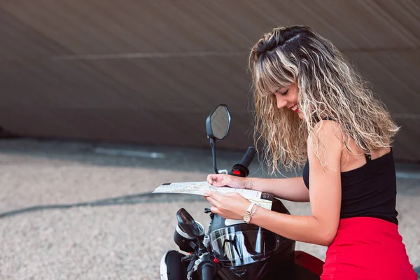 Vacker ung kvinna med karta i handen och en motorcykel. — Stockfoto