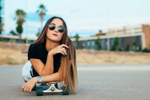 Vacker ung kvinna som ligger på skateboard — Stockfoto