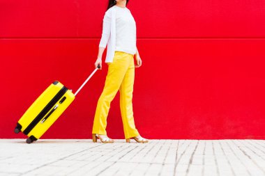 Sarı bavullu kadın caddede yürüyor.