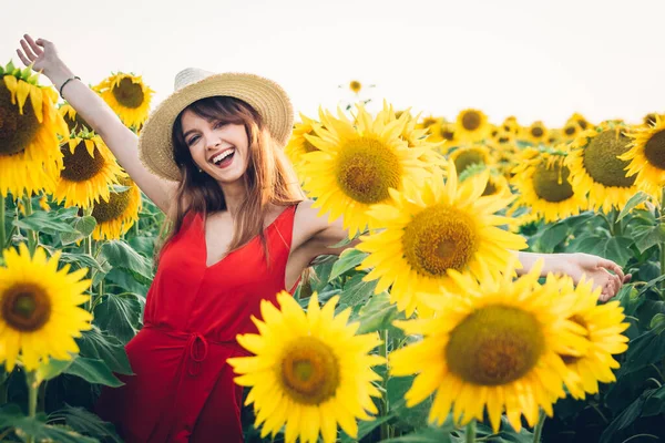 Lycklig kvinna med röd klänning och hatt i fält av solrosor — Stockfoto
