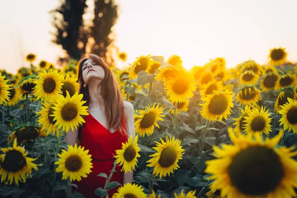 Kvinna med röd klänning i solrosfält — Stockfoto