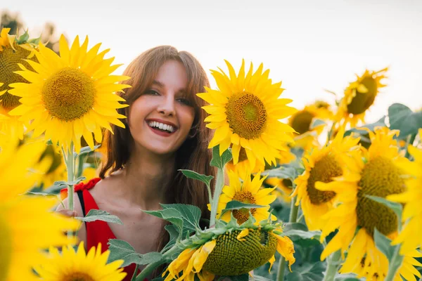 Lycklig kvinna med solros njuter av naturen och skrattar på sommaren solrosfält — Stockfoto