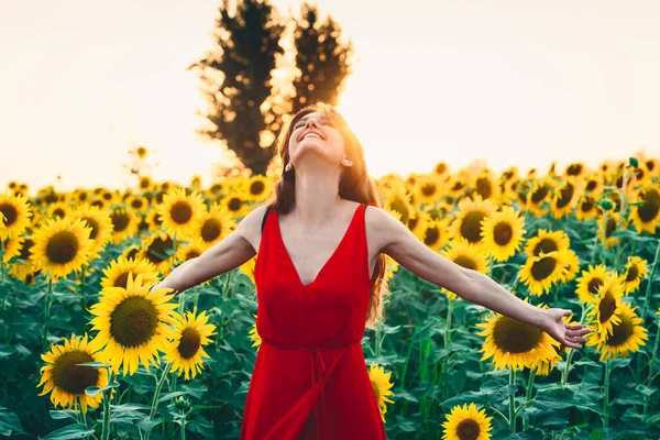 Vacker kvinna med långt hår i ett fält av solrosor. Aktivt, höja — Stockfoto