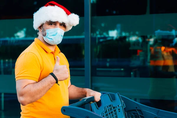 Hombre maduro con máscara médica y compras sombrero de Navidad — Foto de Stock