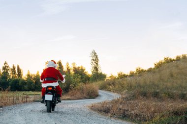 Noel Baba yolda motosiklet sürüyor..