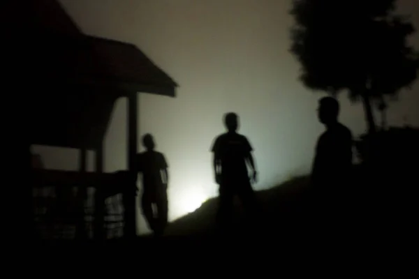 站在雾蒙蒙的夜晚的三个人的影子 — 图库照片
