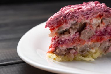 Ringa balığı salatası altında beyaz bir plaka üzerinde bir kürk parçası. Geleneksel Rus katmanlı salatası.