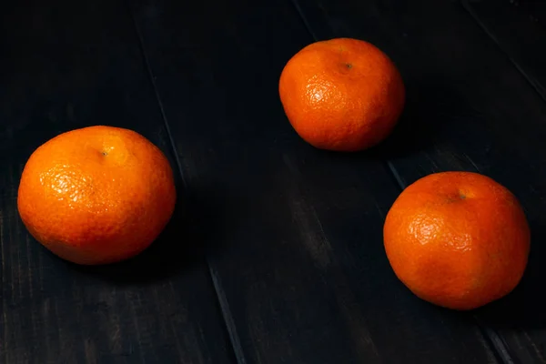 Tangerines on a black wooden background.