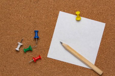 Mantar panoya tutturulmuş beyaz not kağıdı renkli raptiyeler ve kalemle.