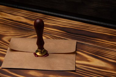 Üzerinde balmumu mühür ve ahşap bir masanın üzerinde bir zarf olan metal mühür.