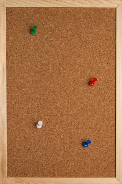 Cork board with pinned colored pins and white note sheets