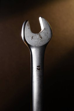 Arka planda sarı bir ışık huzmesi olan karanlıkta paslı bir anahtar.