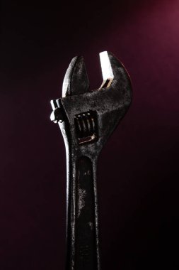 Arka planda kırmızı ışığı olan eski ayarlanabilir İngiliz anahtarı.