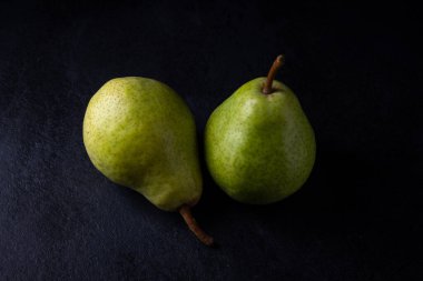 Siyah arka planda iki yeşil armut, sağlıklı yiyecek.