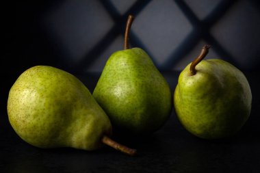 Karanlıkta üç yeşil armut Pencereden gelen şekilli ışık