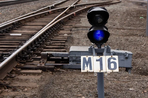 Semaphore with burning blue light. The intersection of railway tracks.