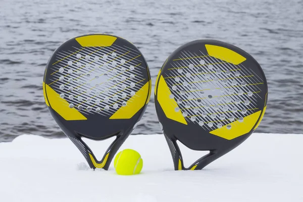 Bola e duas raquetes de tênis de praia na praia coberta de neve agai — Fotografia de Stock