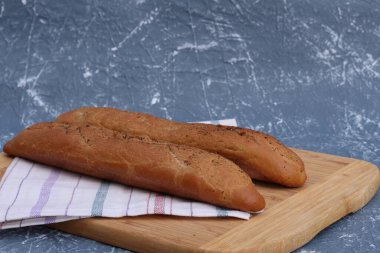 İki taze ekmek pişirdikten sonra soğur. Ekmek havlunun üzerinde, ahşap bir arka planda. Metin için alanı kopyala.