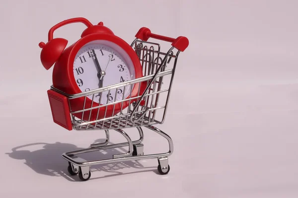 stock image Clock in a mini shopping trolley on a white background. Shopping time concept.