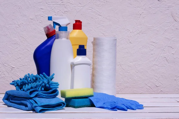 Household cleaning products on a white wooden background. House disinfection.