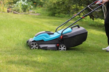 Çiftçi çim biçme makinesiyle çim biçiyor. Bahçe bakımı