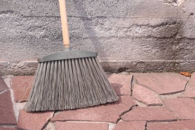 Taş bir yüzeyde sert plastik tüyleri olan süpürge..
