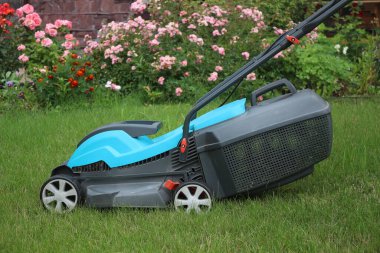 Bir çim biçme makinesi yeşil çimlerin üzerinde duruyor. Yakın plan..