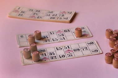 Pembe arka planda loto ve oyun kartları olan eski fıçılar.