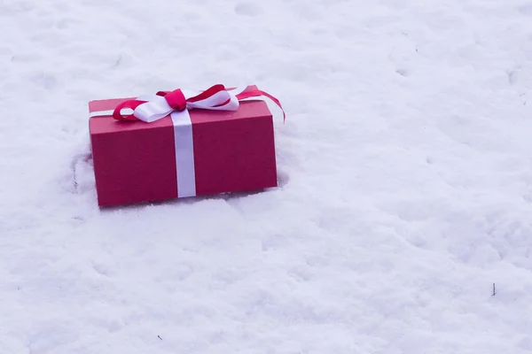 red gift box lies on white snow
