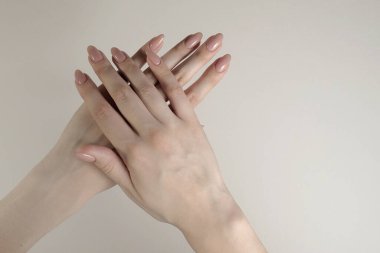 Beyaz arka planda bej manikürlü güzel kadın elleri.