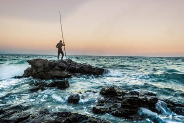 Genç adam bir kayaya gece karanlığında kıyıya vurdu bir fırtına ortasında durdu.