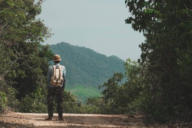 Ormana giden yolda duran ve sırt çantasıyla dağlara bakan adam. yaz tatilleri ve vahşi içine açık tek başına Seyahat Lifestyle wanderlust macera için kavram, Phang Nga, Koh Yao Yai, Tayland