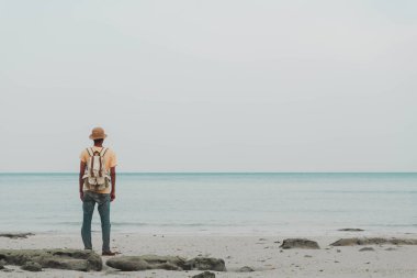 young man with backpack standing on beach and looking to horizon of ocean. concept for adventure and travel sea in  summer vacations and outdoor alone,sea south Thailand,koh yao yai