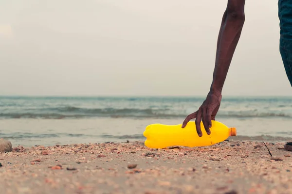 Bir el sahilde dökülen çöptoplamak. Boş kullanılmış kirli plastik şişeler. okyanus çevre sorunu Plastik kirliliği için kavram